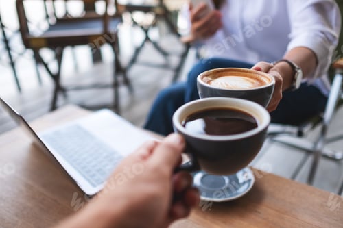 Preview: Two businessman clinking coffee cups together while working and meeting
