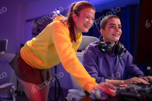 Preview: Two woman gamers wearing headsets playing a video game together in a colorful gaming room