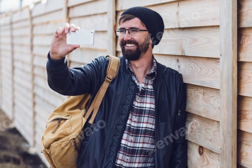 Preview: Hipster man making selfie on smartphoneby mobile phone