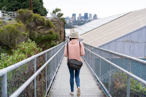Preview: view of lady from behind walking on the walkway bridge