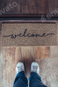 Preview: High angle view of welcome mat in door over wooden floor with woman foot-ware near of it