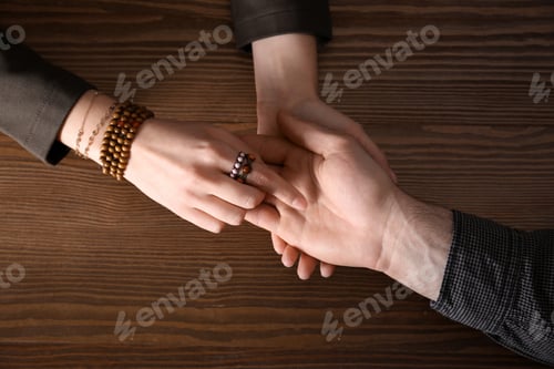Preview: Chiromancer reading lines on man's palm at table, above view