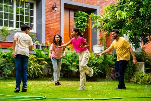 Preview: Indian family playing Langdi or one-leg hop game in garden, enjoying energetic outdoor fun