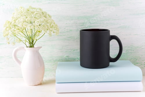Preview: Black coffee mug mockup with tender white flowers and books