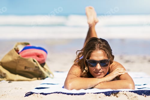 Preview: Working on that tan. Portrait of a beautiful young woman lying on a towel at the beach.