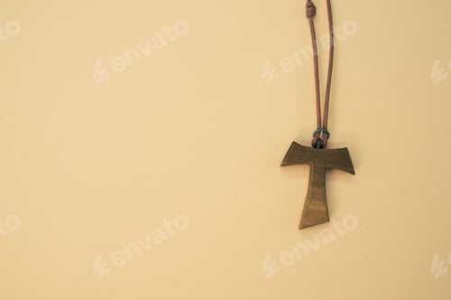 Preview: Closeup shot of a wooden tau cross necklace isolated on a brown background