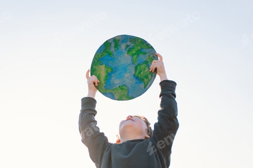 Preview: Little boy holding planet in hands against green spring background. Earth day