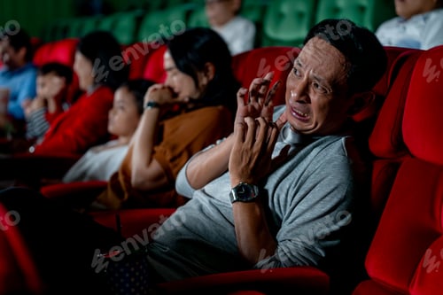 Preview: Close up Asian man look scary or panic during watch movie with his family in cinema theater