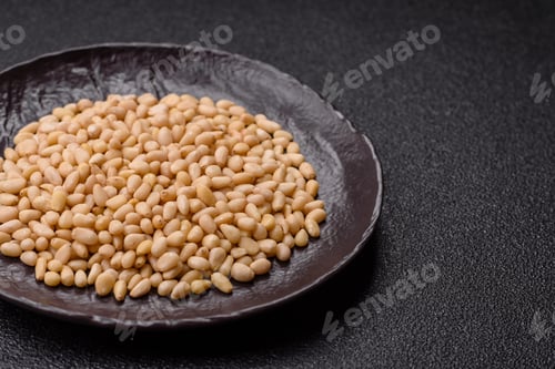 Preview: Peeled pine nuts in a bowl on a dark concrete background