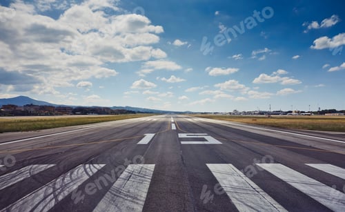 Preview: Empty runway stretching into the horizon under a wide blue sky.
