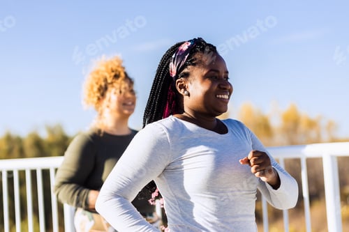 Preview: Two excited young plus size women jogging together.