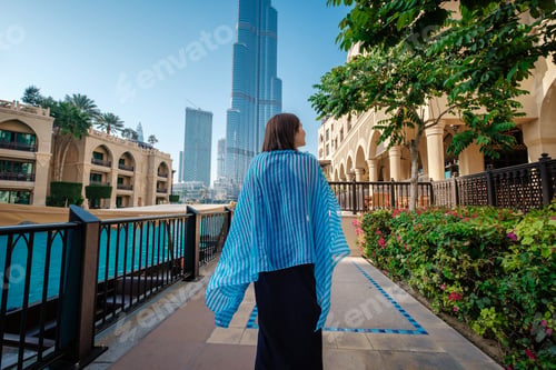 Preview: Enjoying travel in United Arabian Emirates. Young woman in dress walking on Dubai Downtown.
