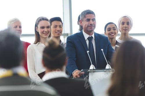 Preview: Businessman standing on podium with diverse colleagues and speaking at business seminar in office