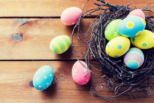 Preview: close up of colored easter eggs in nest on wood