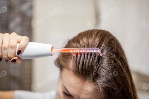 Preview: Woman uses darsonval for massage head's skin.