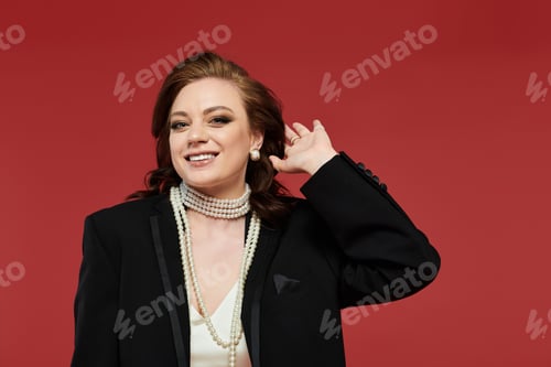 Preview: A graceful young woman in elegant attire poses against a vibrant red backdrop, radiating confidence