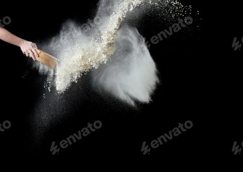 Preview: Female hand sifts white wheat flour through a round wooden sieve on a black background