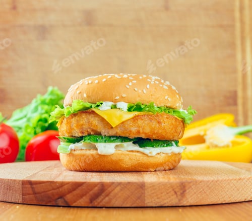 Preview: Delicious chicken sandwich with fresh vegetables on a wooden cutting board in a bright kitchen