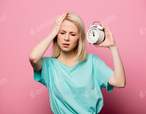 Preview: Beautiful blonde woman with alarm clock on pink background