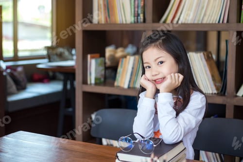 Preview: Little girl, Asian teen, sitting bright smile happily in the library.