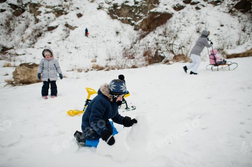 Preview: Family plays and sleigh rides in winter outdoor, mother and children having fun.