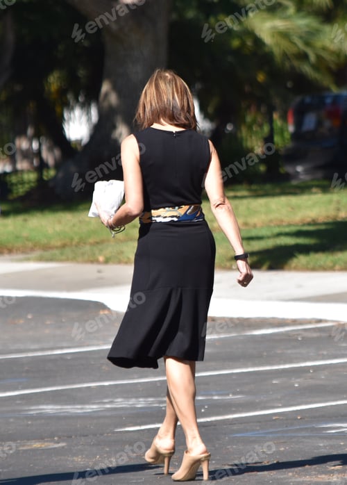 Preview: Dressed up business woman in black with a clutch purse
