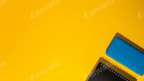 Preview: Top view of a smartphone and a notepad on a yellow background