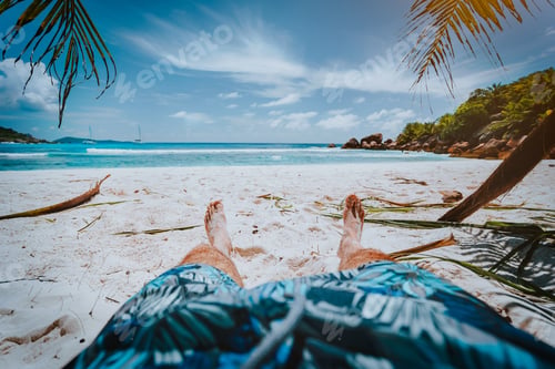 Preview: POV shot of man wear blue swimming shorts laying on a beautiful sandy tropical beach Anse Cosos, La
