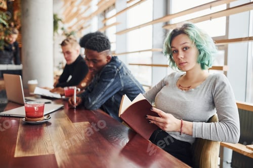 Preview: Alternative girl with green hair is sitting against group of multi ethnic people