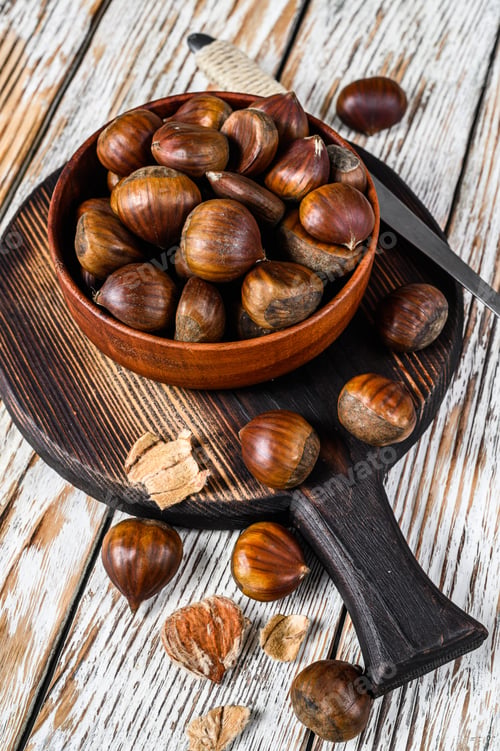 Preview: Bowl with chestnuts on a wooden table. White background. Top view