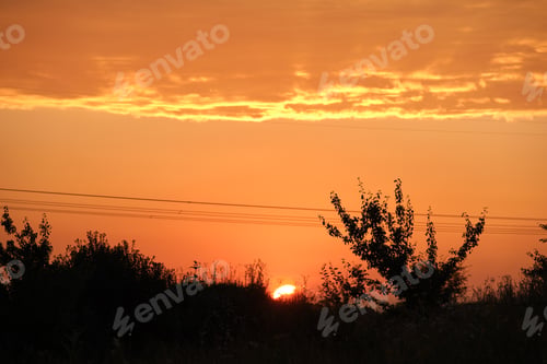 Preview: Dark silhouette of high voltage towers with electric power lines at sunrise.