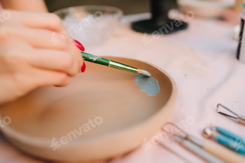 Preview: Artist applying paint to ceramic bowl, demonstrating creative process