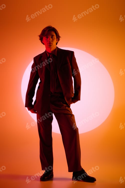 Preview: Stylish young man posing confidently against a vibrant orange backdrop