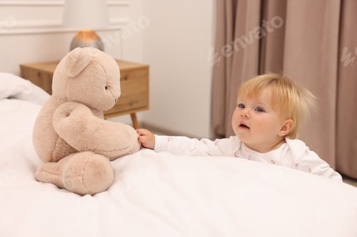 Preview: Cute baby taking toy bear from bed at home