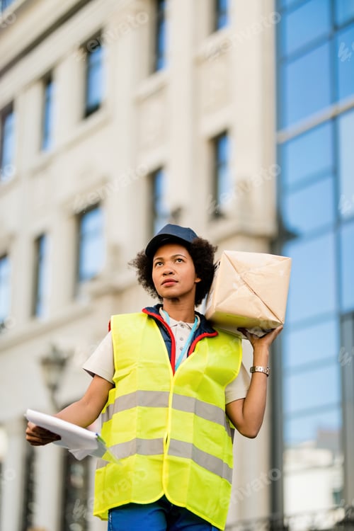Preview: Below view of female African American deliverer with a package in the city.