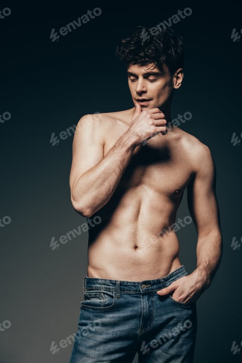 Preview: handsome tender man in jeans posing isolated on dark grey