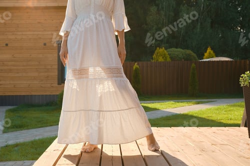 Preview: Barefoot legs of a woman visible through a thin dress