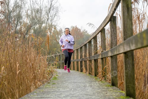 Preview: Healthy fit woman running through the park keeping fit