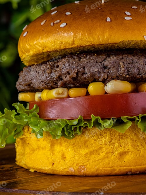 Preview: Delicious cheeseburger served with freshly-sliced tomatoes and corn on the cob, on a tabletop