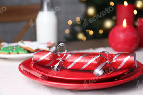 Preview: Red plate with Christmas cracker on table, closeup