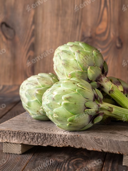 Preview: Fresh raw artichokes on vintage cutting board with rustic wooden background texture