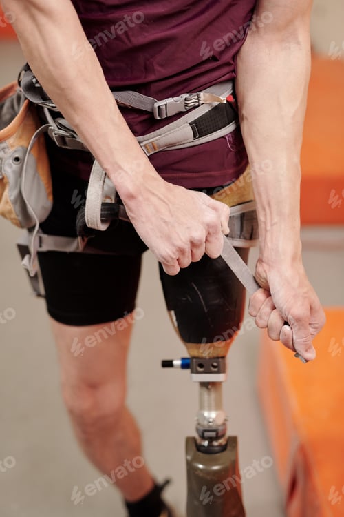 Preview: Young man with physical disability fixing climbing equipment