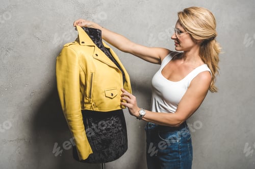 Preview: attractive mature dressmaker with yellow leather jacket on mannequin