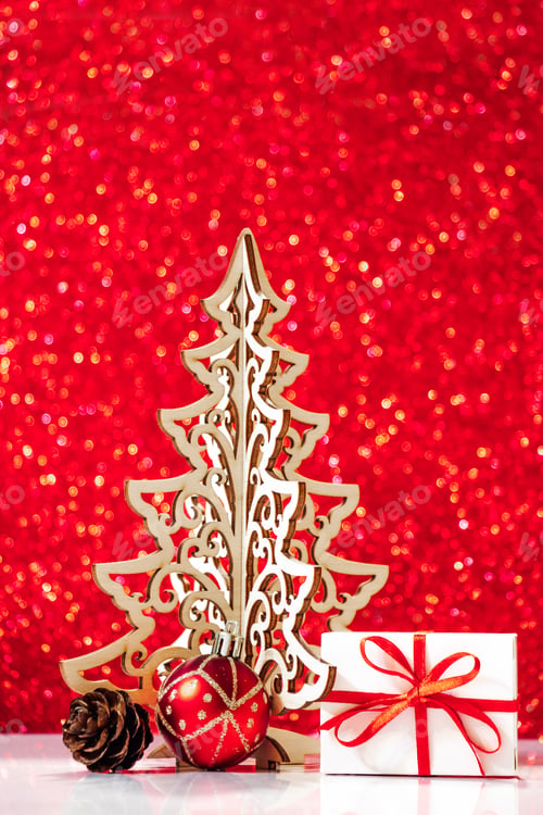 Preview: Decorative wooden Christmas tree and gifts on red glittering background.