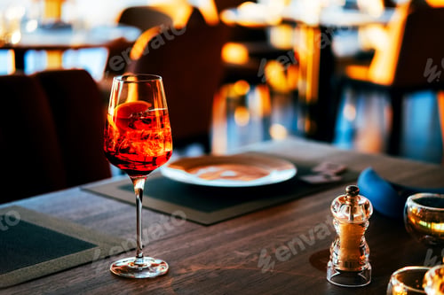 Preview: Big glass with orange cocktail on the table in restaurant