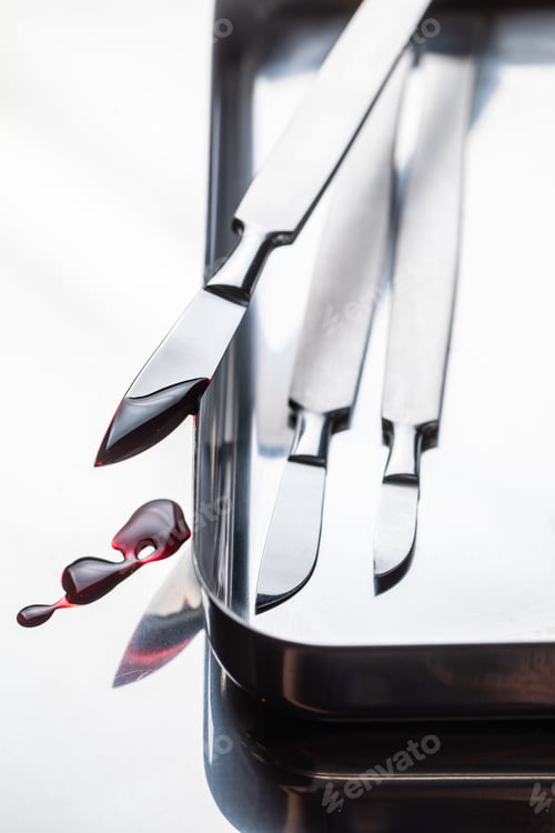 Preview: Closeup of scalpels on stainless steel table with blood