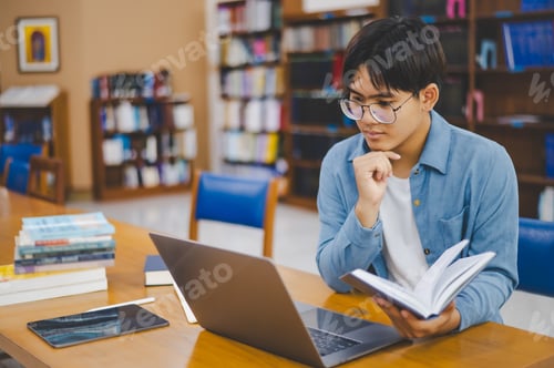 Preview: Male college students are working on laptops and searching for books to study