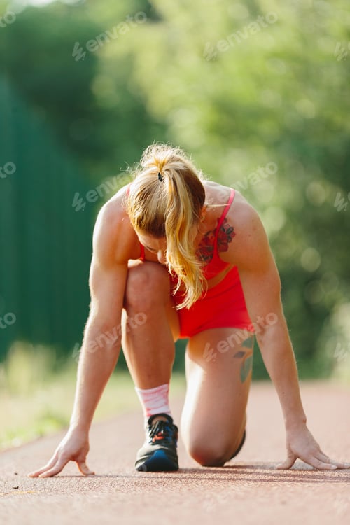 Preview: Woman starting race on track doing training outdoor