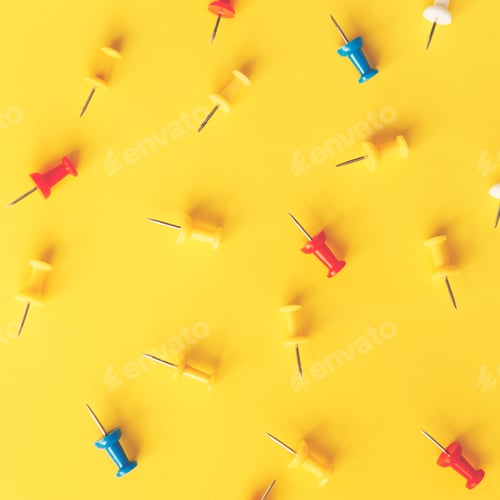 Preview: A lot of colorful paper clips lie on an yellow background.