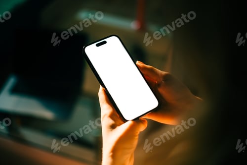 Preview: Woman holding mobile phone with white screen mock up, resting on a sofa in living room at home.